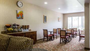 Uma área de jantar de hotel com buffet, relógio e quadros nas paredes.