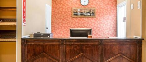 A reception desk with a clock, a framed picture, and a Coca-Cola sign on the wall.