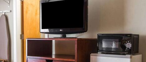 Una habitación con un armario de madera, un televisor y un microondas.