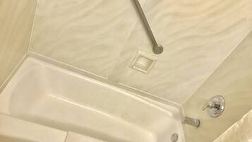 A bathroom with a bathtub, a towel, and a showerhead.