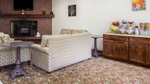 A living room with a fireplace, sofa, coffee table, and a dining area with a buffet setup. - Econo Lodge Lake Region (West Ossipee)