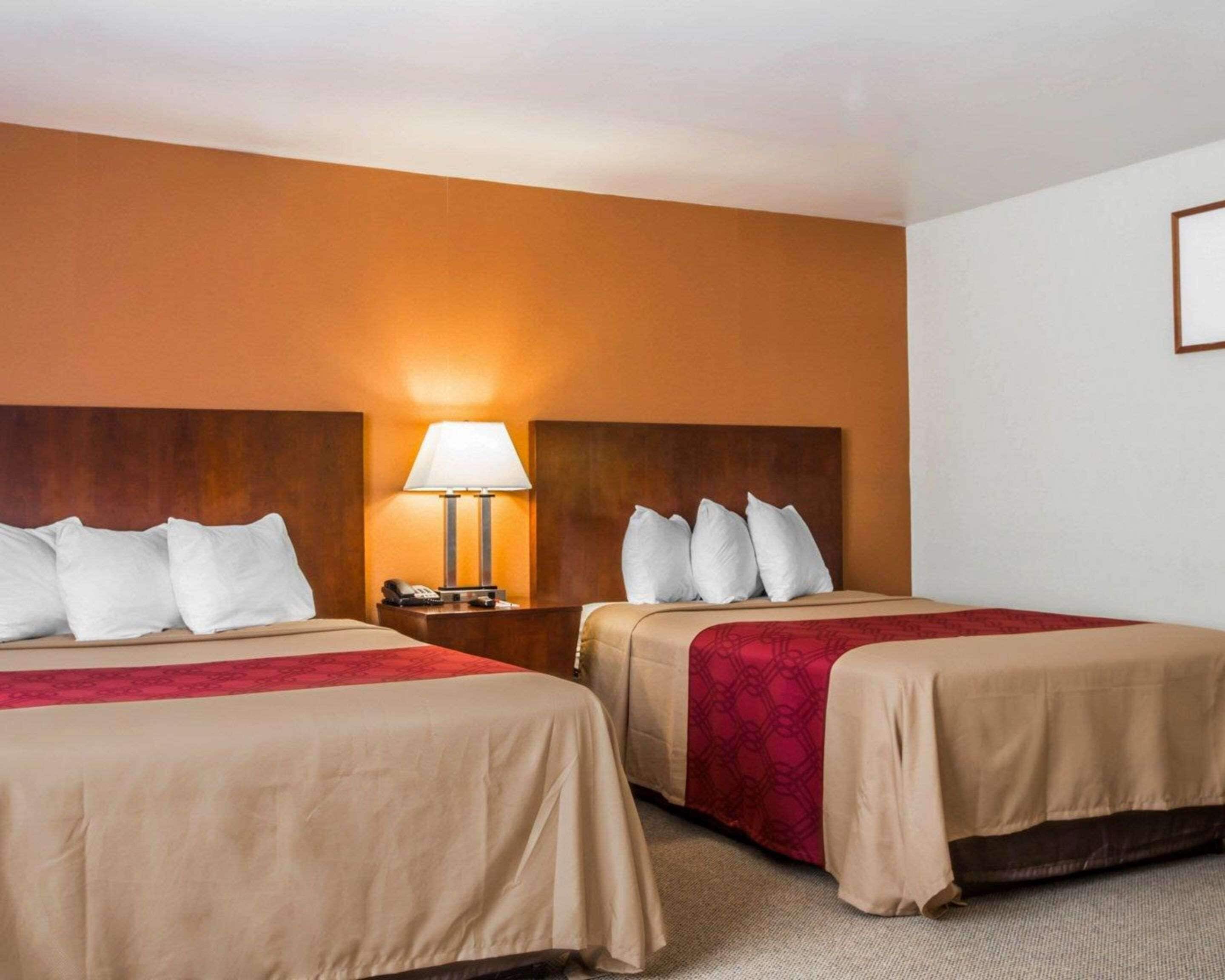 A hotel room with two beds, a nightstand with a lamp, and a framed picture on the wall.