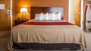 A hotel room with a large bed, a nightstand with a lamp, and a door with a fire evacuation plan. - Econo Lodge Lake Region (West Ossipee)