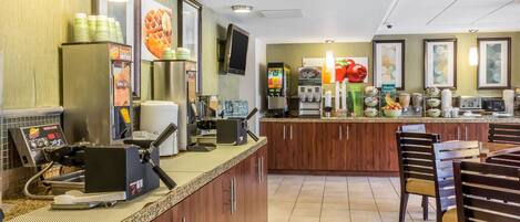 Un restaurante con mostrador, zona de mesas y varios dispensadores de comida y bebida.