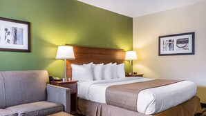 A hotel room with a bed, a sofa, a nightstand, and two lamps. - Quality Inn Flamingo (Atlantic City)