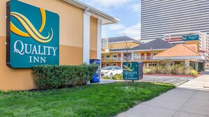 A Quality Inn hotel with a clear sign, a parking lot, and a building in the background. - Quality Inn Flamingo (Atlantic City)
