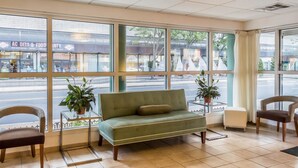 A green sofa, two chairs, and a small table with potted plants in a room with large windows. - Quality Inn Flamingo (Atlantic City)