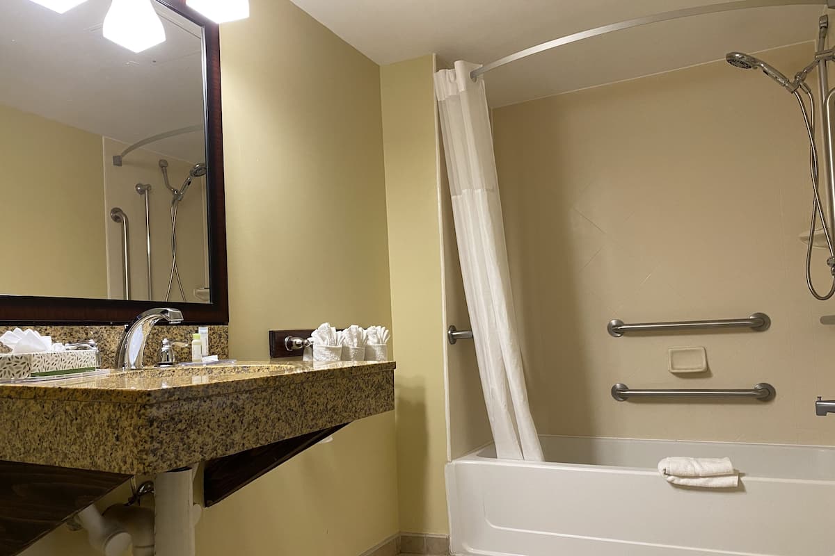 A bathroom with a sink, mirror, shower, and bathtub.