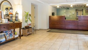 A hotel reception area with a wooden desk, a mirror, and a plant. - Quality Inn Flamingo (Atlantic City)