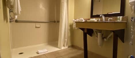 A bathroom with a shower, a sink, a mirror, and a hairdryer.