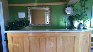 Un comptoir d’accueil avec un revêtement en bois, un miroir au-dessus et une horloge au mur.