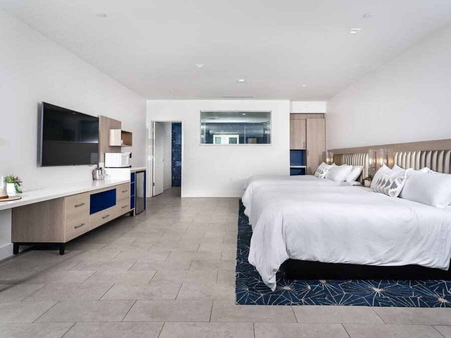 Quarto de hotel moderno com uma cama grande, uma mesa e uma televisão de tela plana, e um banheiro separado.