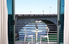 A view from a balcony with a table and chairs, overlooking a bridge with a boat and flags. - Heat Hotel (Lake Havasu City)