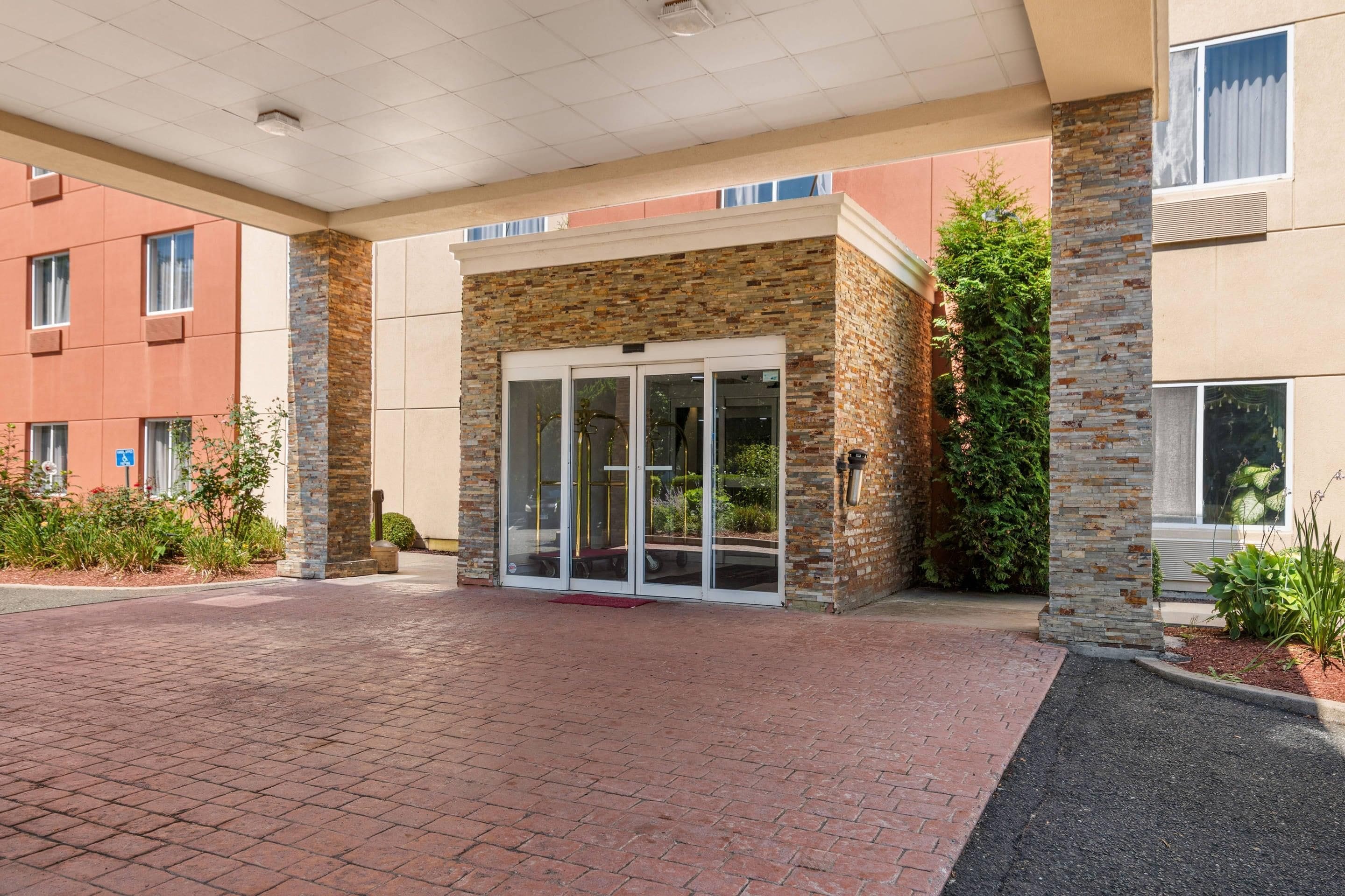A building entrance with a brick facade, glass doors, and a paved walkway.