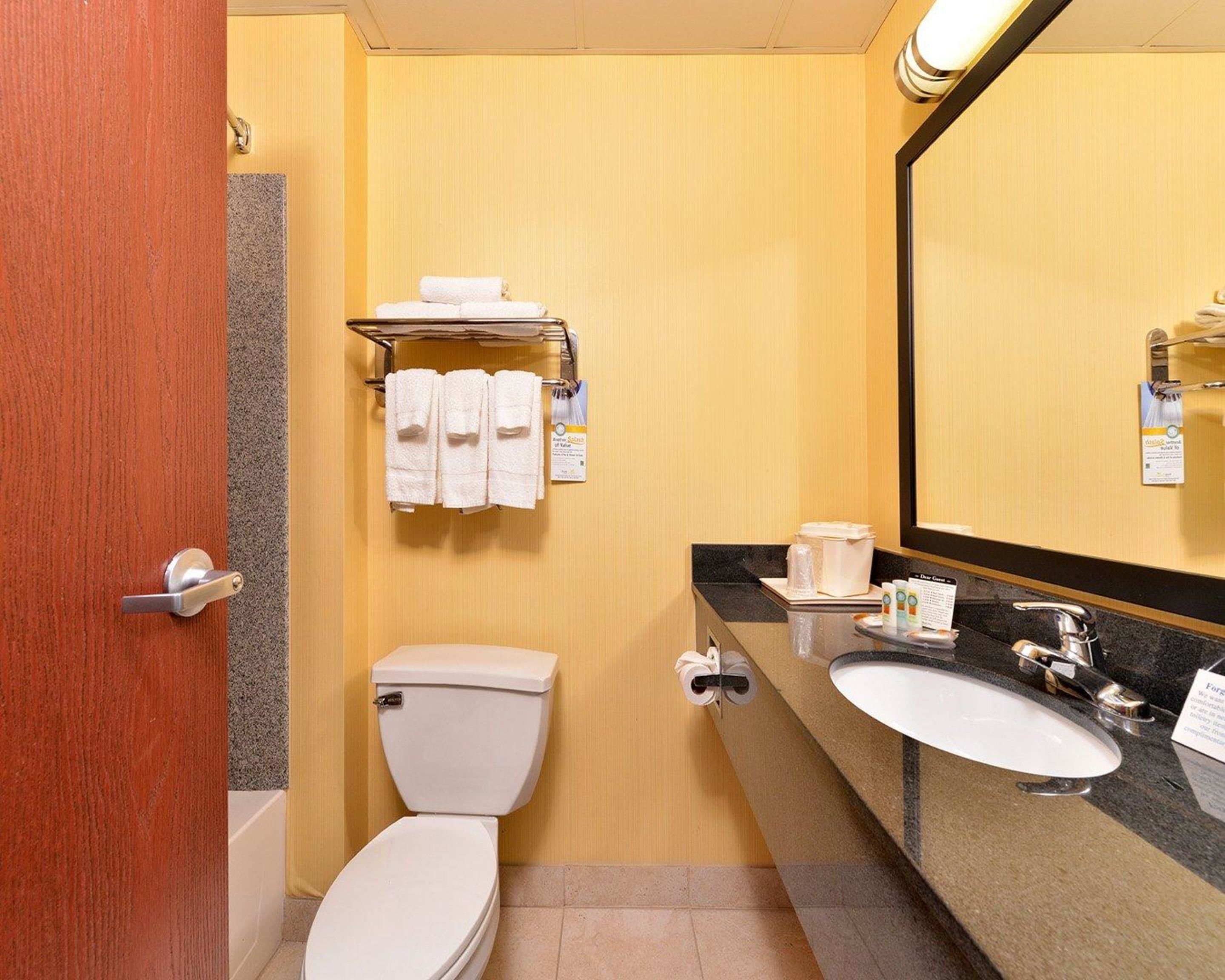 Une salle de bain d’hôtel équipée de toilettes, d’un lavabo et d’un miroir.