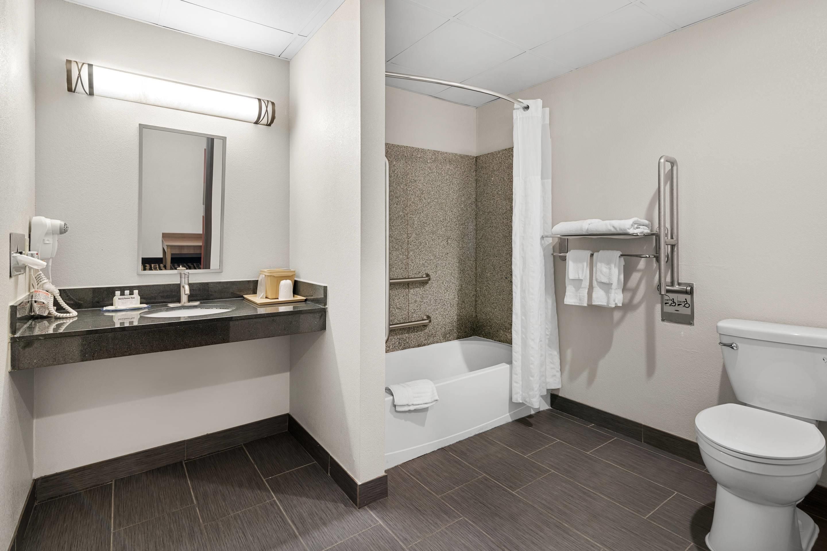 A modern bathroom with a sink, mirror, towel rack, shower, and toilet.
