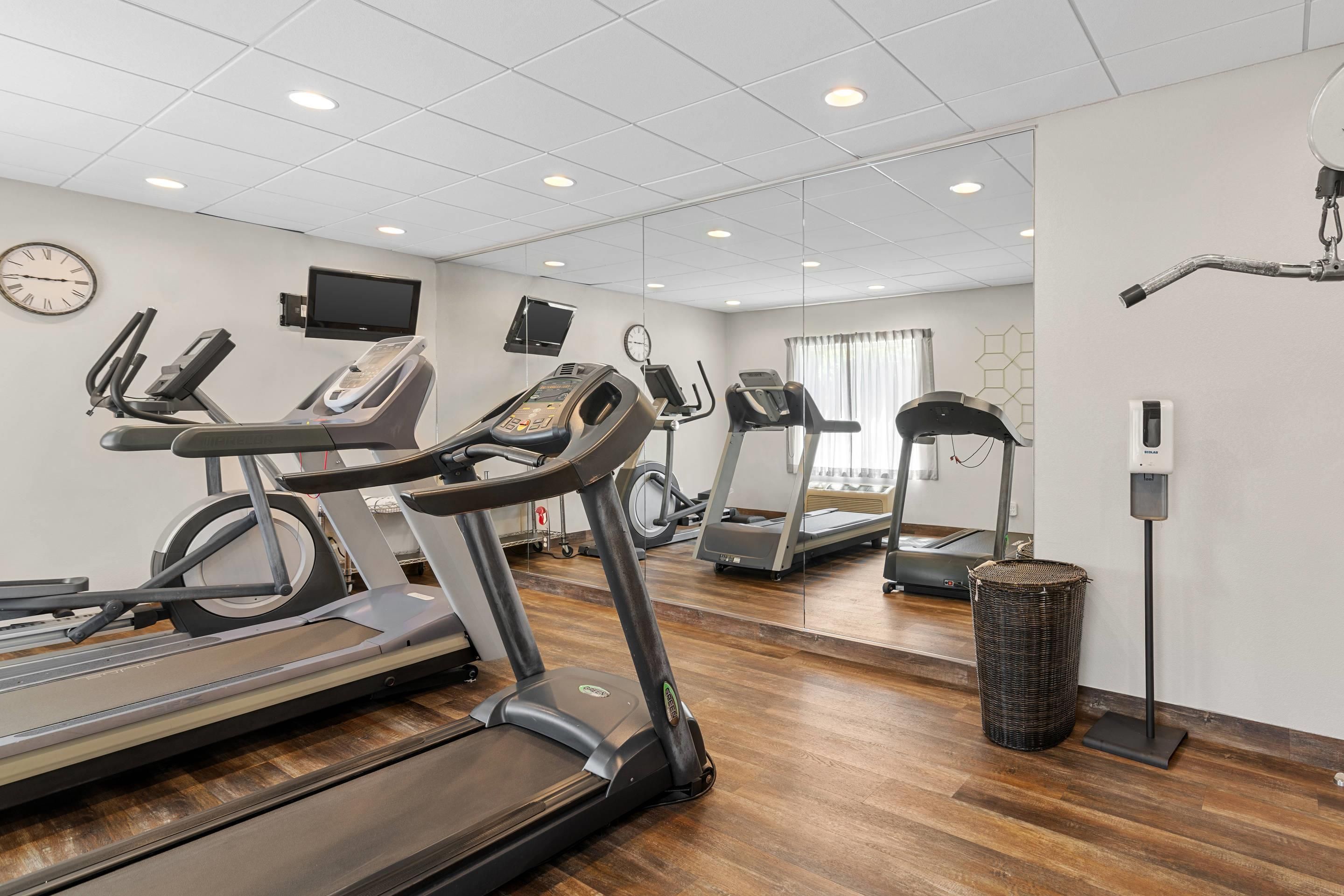 A gym with multiple treadmills, exercise bikes, and a mirrored wall.