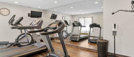 A gym with multiple treadmills, exercise bikes, and a mirrored wall.