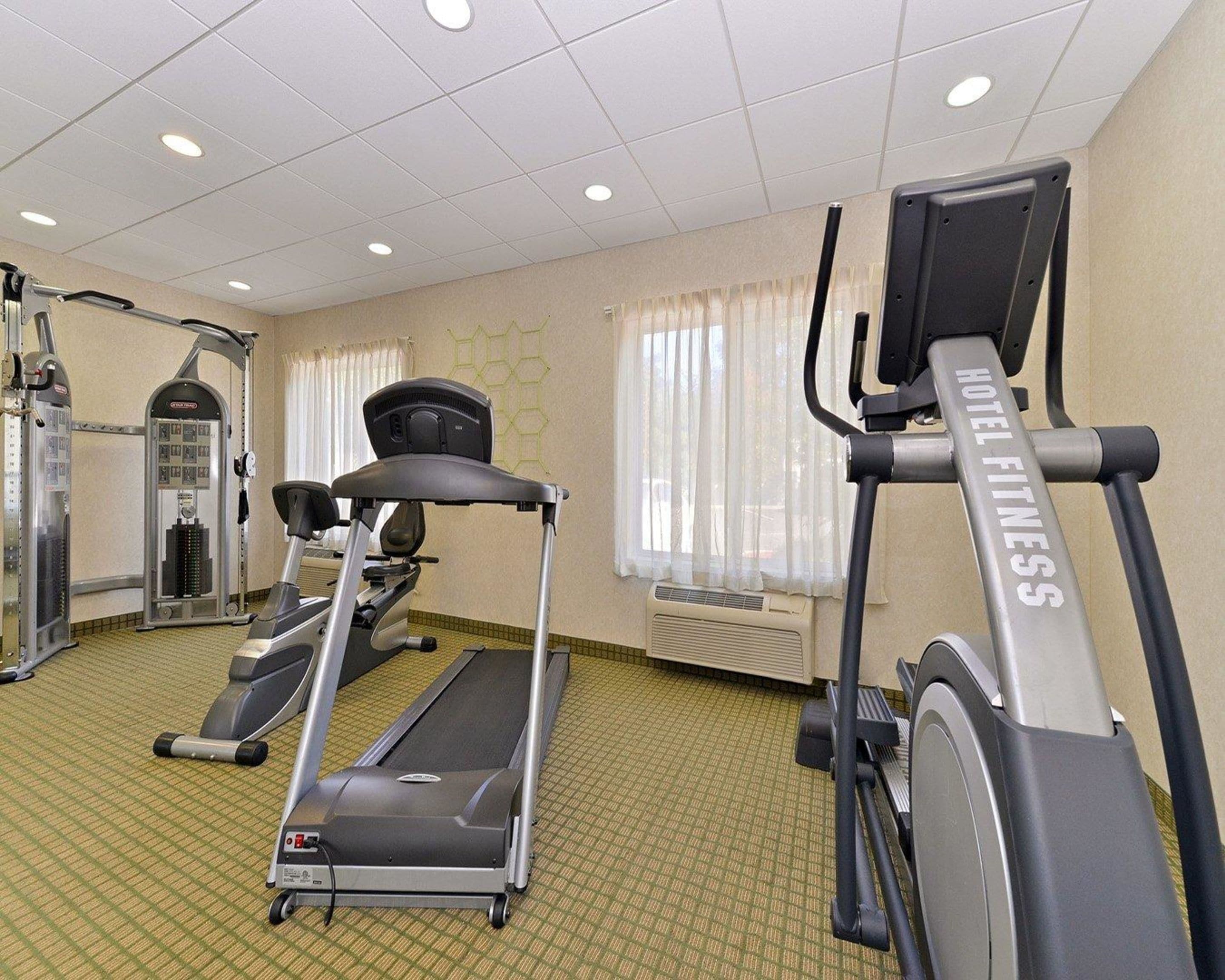 Un gimnasio de hotel con cintas de correr, elípticas y equipo de pesas.