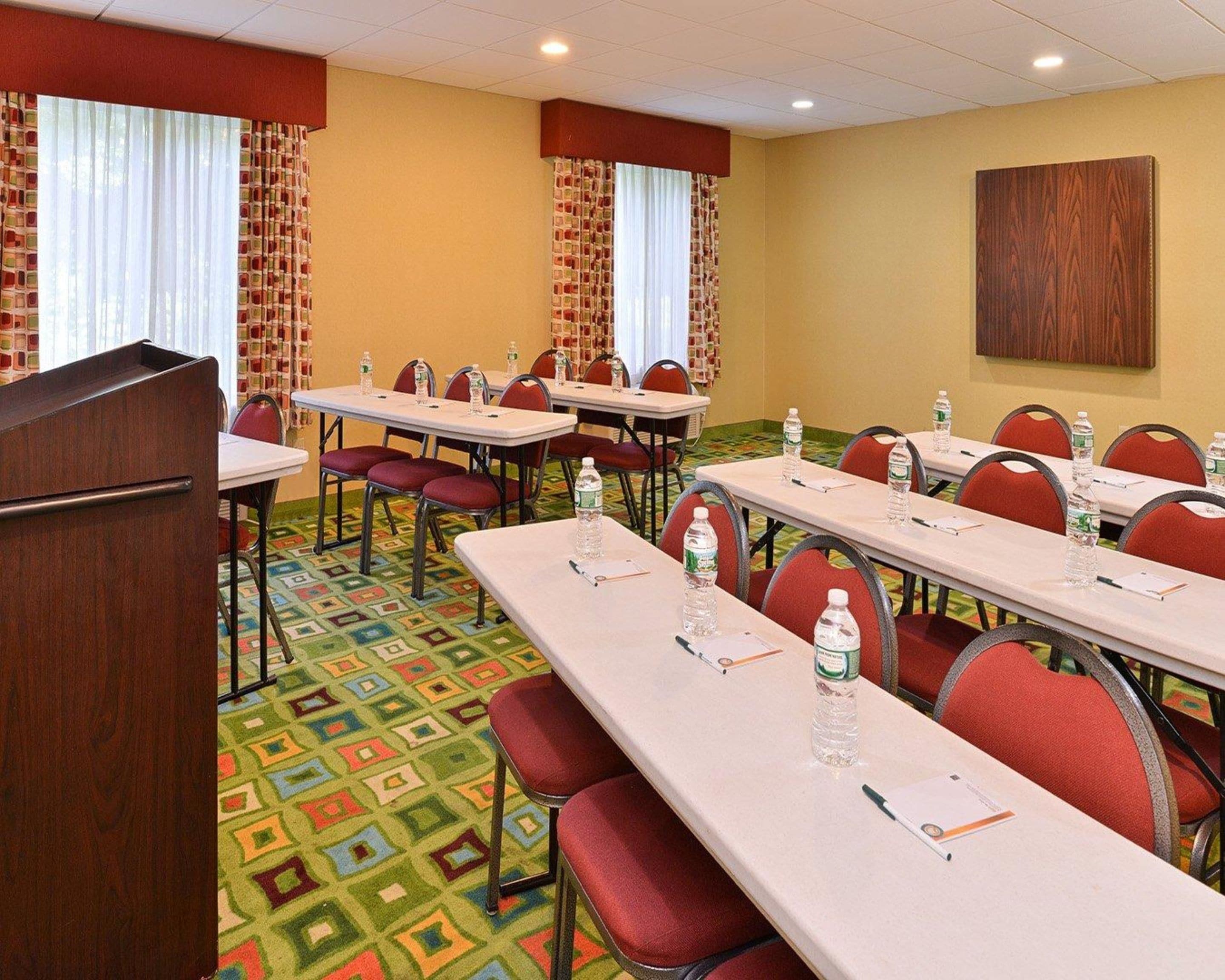 A conference room with multiple tables, chairs, and water bottles.