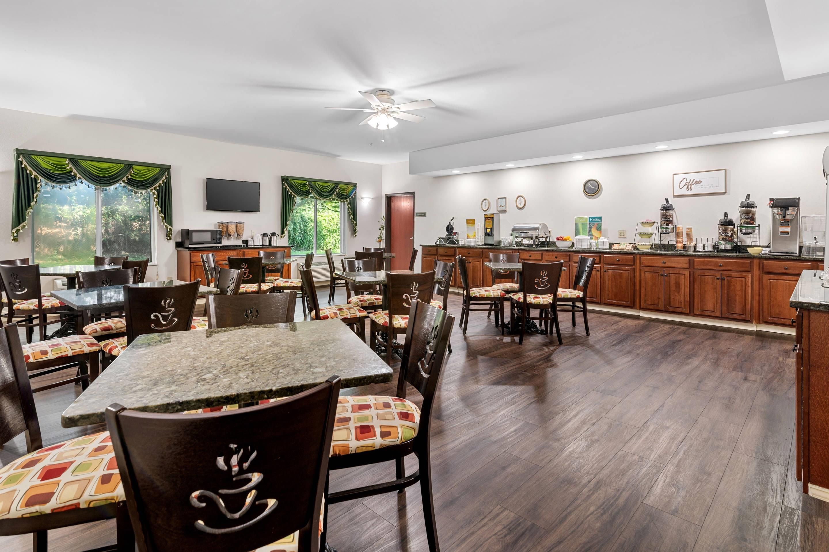 A spacious dining area with a high ceiling and a ceiling fan, wooden cabinets, and a kitchen area with a coffee station.