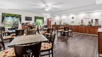 Un comedor espacioso con techo alto y ventilador de techo, armarios de madera y una zona de cocina con estación de café.
