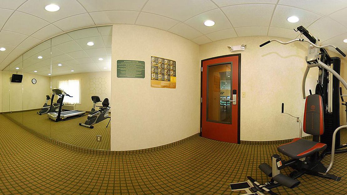 Un gimnasio con cintas de correr, máquinas de pesas y un muro de espejos.