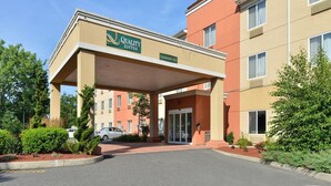 Entrada de un hotel con un cartel que dice "Quality Suites" y un cielo despejado.