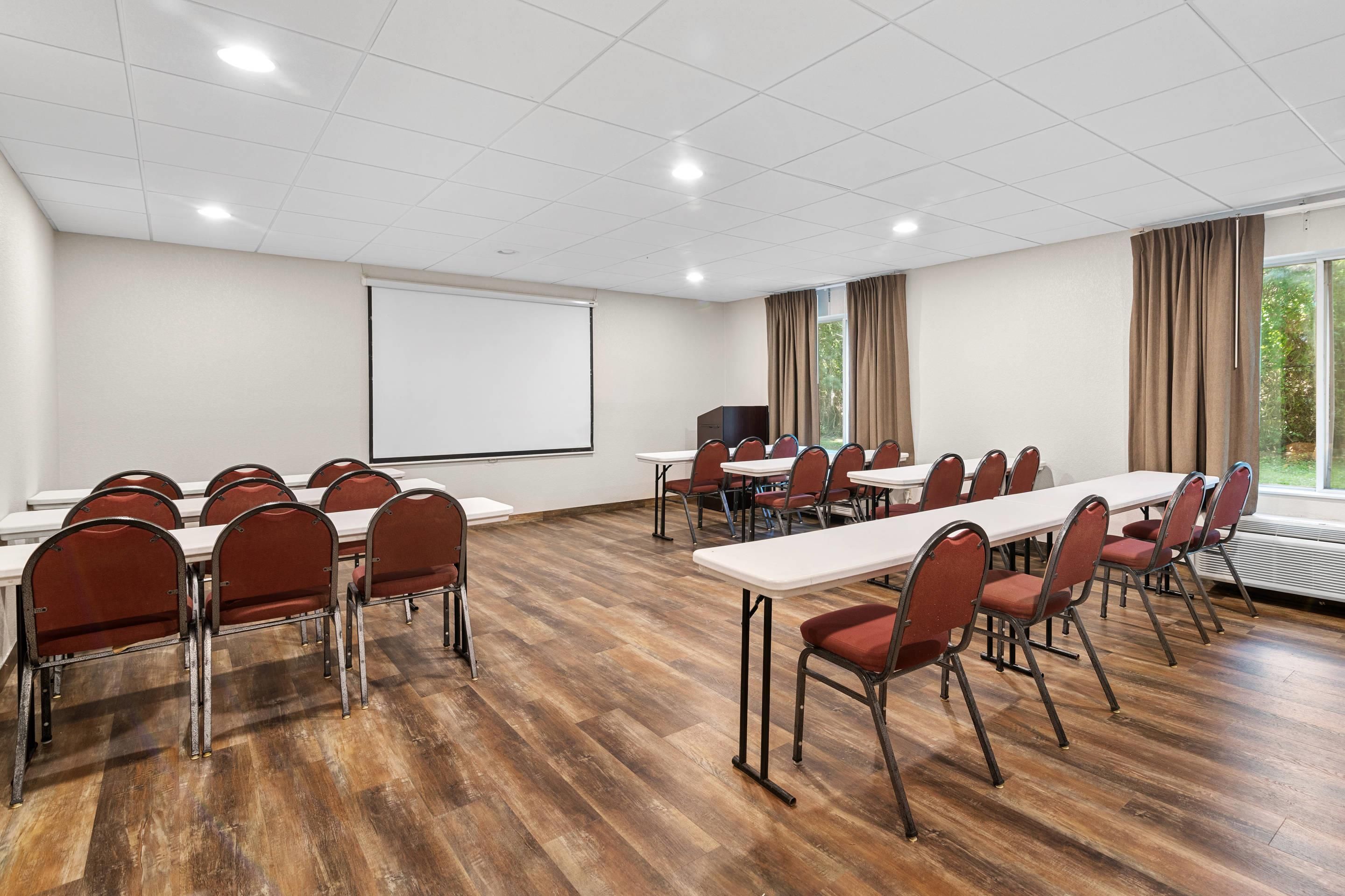 A conference room with a whiteboard, projection screen, and large windows with curtains.