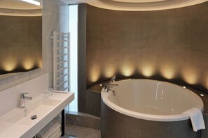 A modern bathroom with a large bathtub, a white vanity with a mirror, and a towel rack. - Clarion Congress Hotel Prague (Prague)