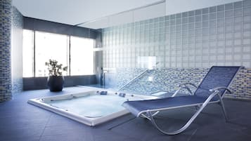 Relax by the pool surrounded by a blue and white tile design, featuring a lounge chair and lush greenery.