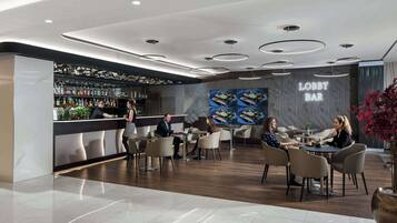 A modern lobby with a bar area, seating arrangements, and a decorative wall with a 'Lobby Bar' sign.