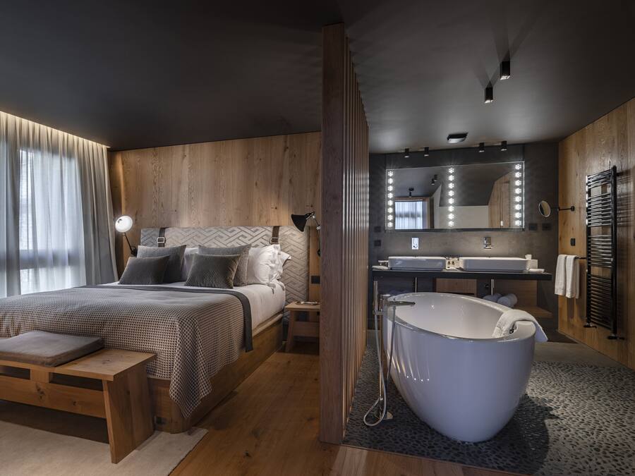 Un dormitorio moderno con una cama grande, mesita de noche y bañera integrada.