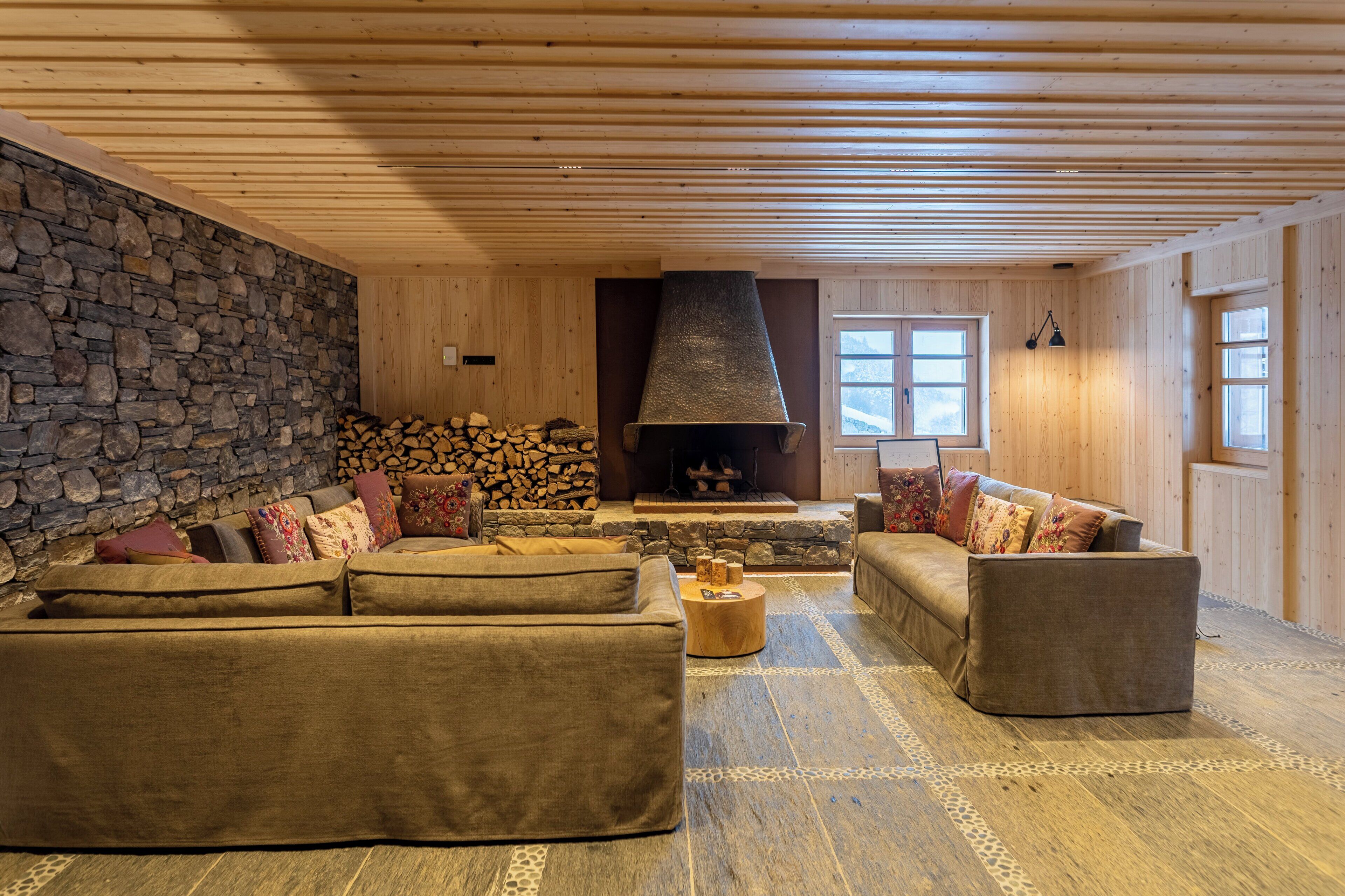 A cozy living room with a stone wall, a fireplace, and wooden flooring.