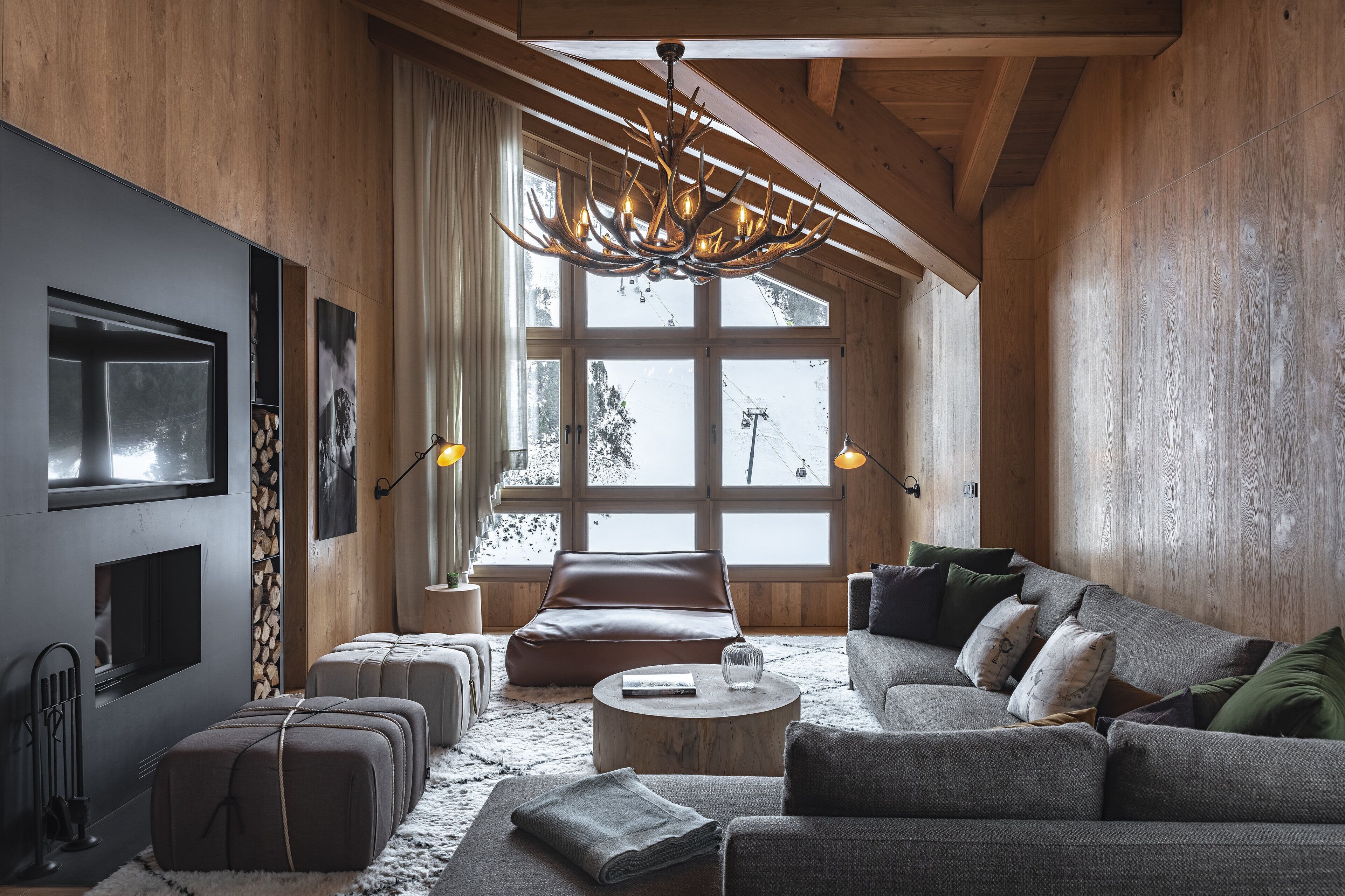 A spacious living room with a large window, a fireplace, a sofa, and a chandelier.