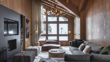 A spacious living room with a large window, a fireplace, a sofa, and a chandelier.