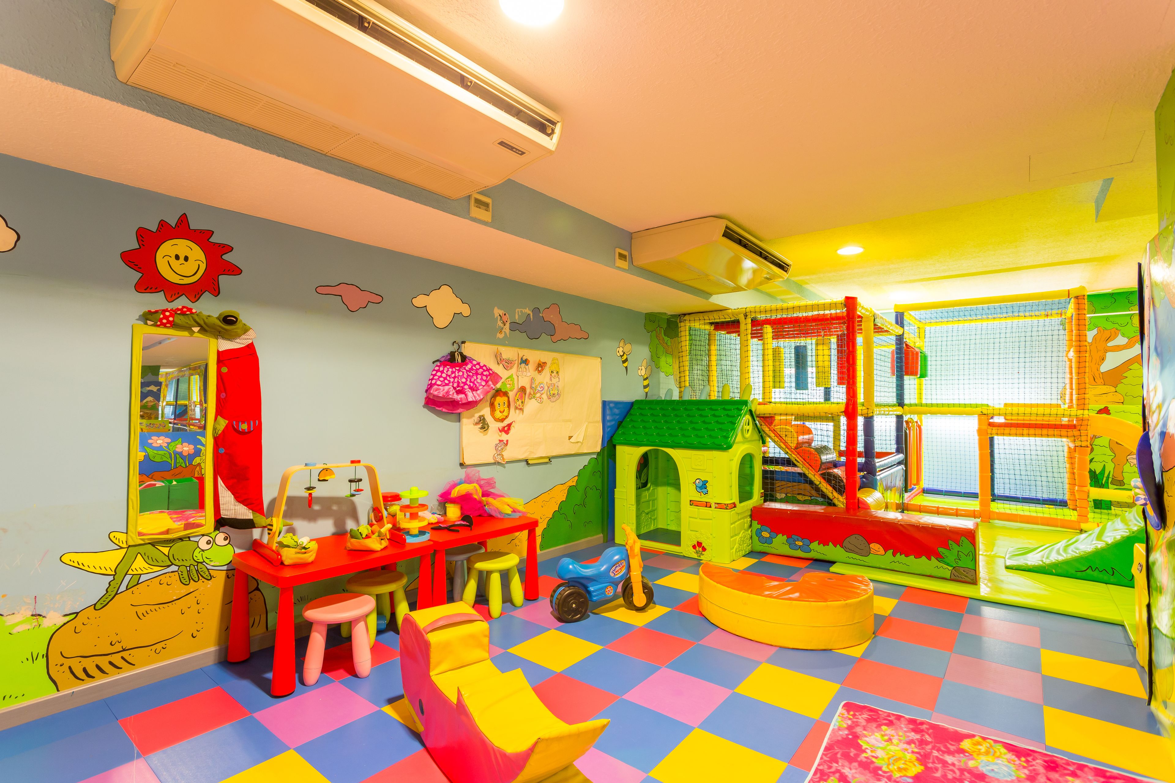 A brightly colored playroom with a slide, playhouse, and various toys.