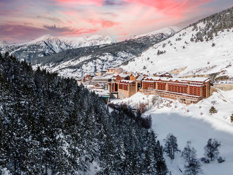 A snow-covered mountain resort with a large lodge featuring multiple floors and a central courtyard.