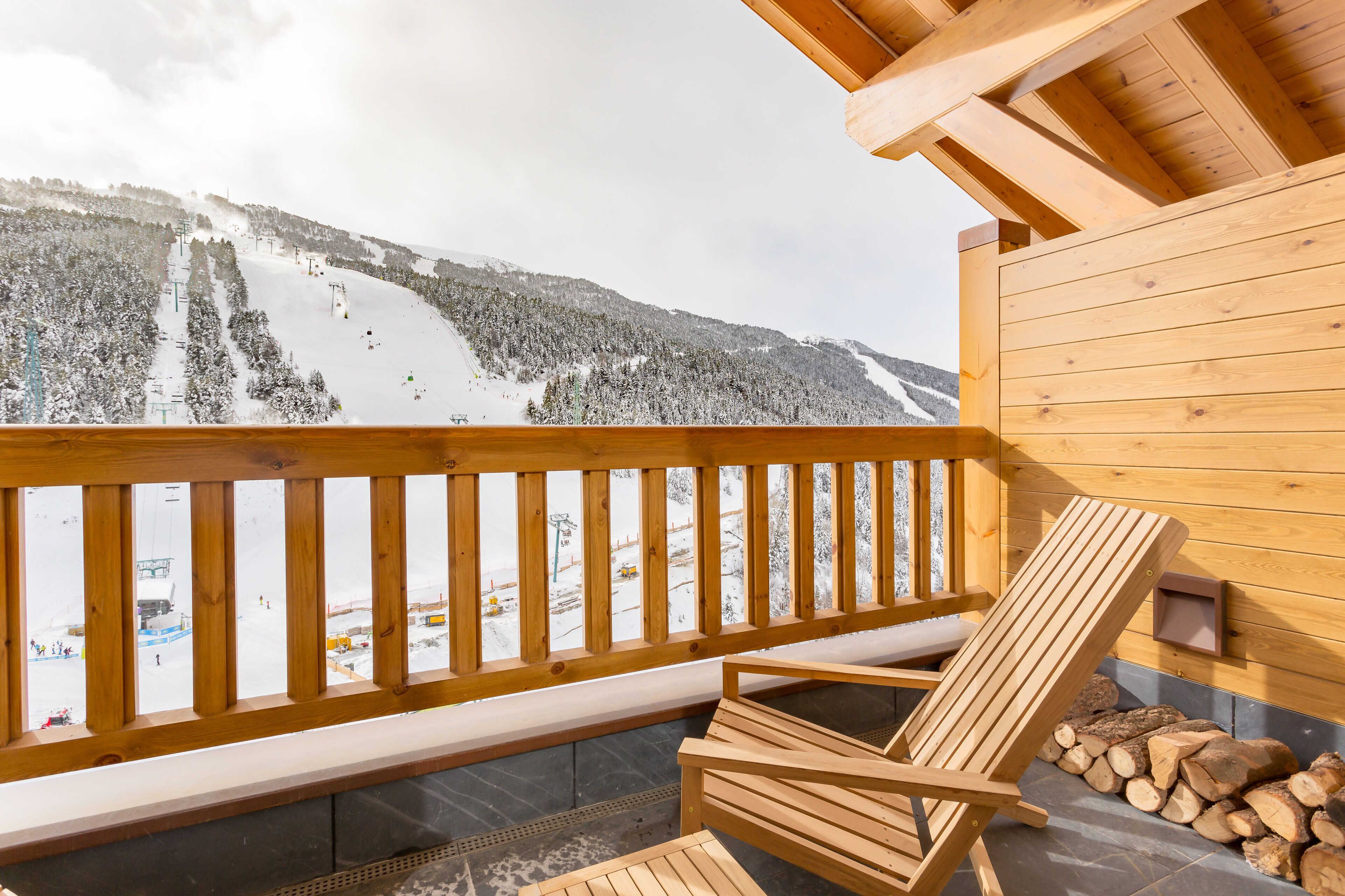 A wooden balcony with a view of a snow-covered ski slope.