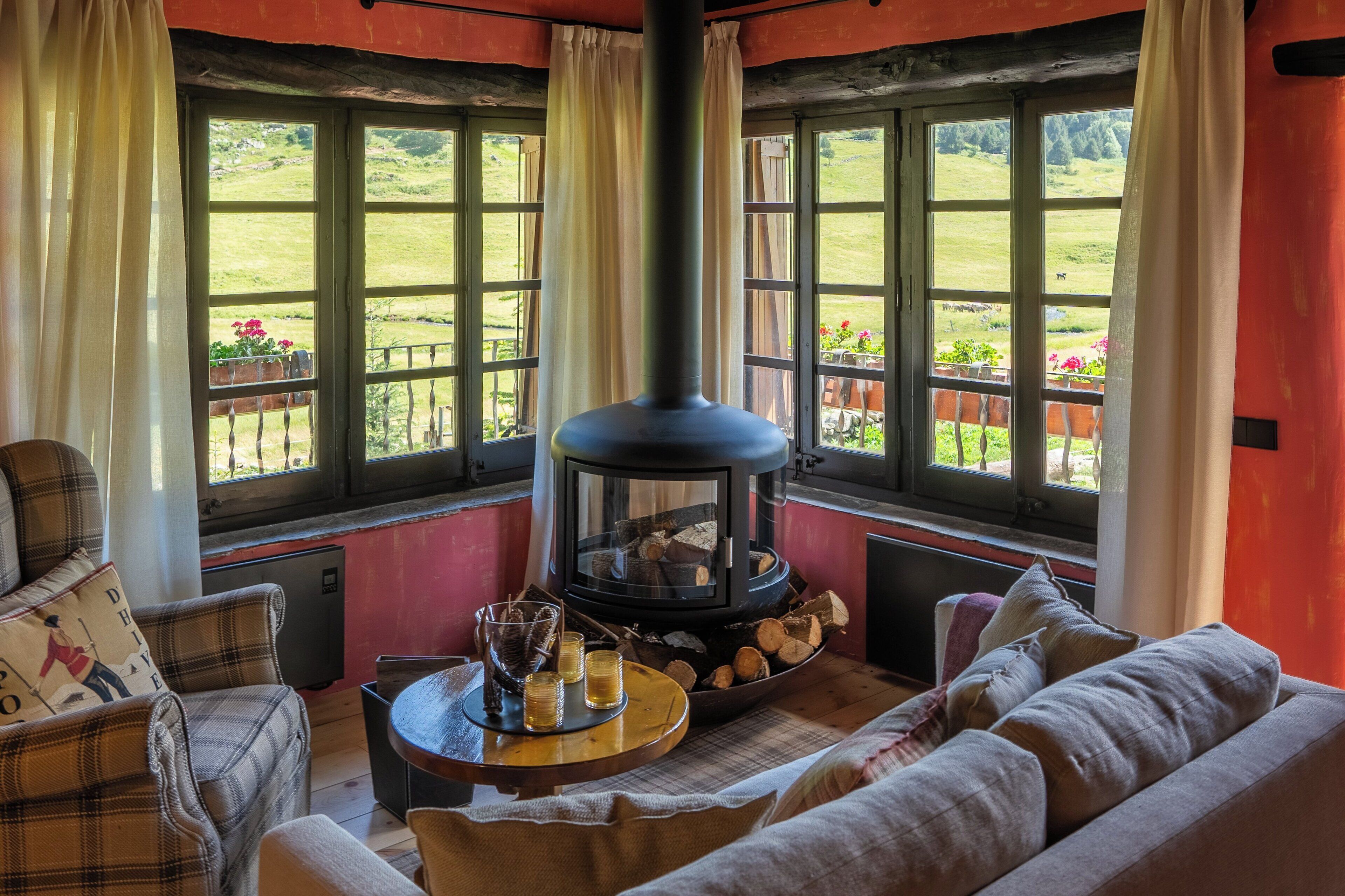A cozy room with a fireplace, a sofa, and a table with glasses and a tray of logs.