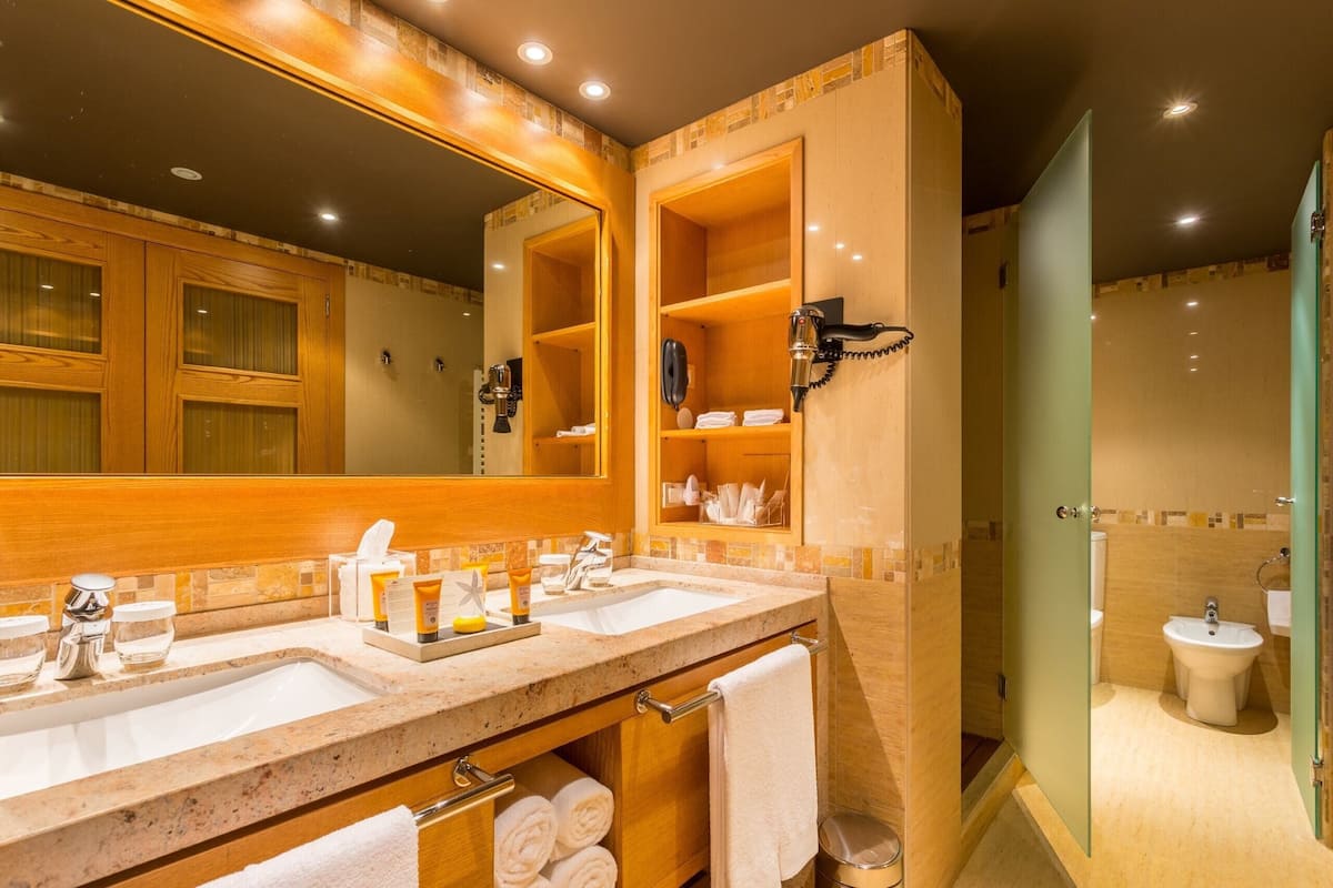 Casa de banho com duas pias, um espelho grande e cabine de duche em vidro.