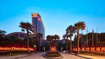 A hotel entrance with a prominent sign, palm trees, and a tall building in the background.