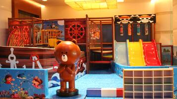 A children's play area with a bear statue, slides, and a play structure.