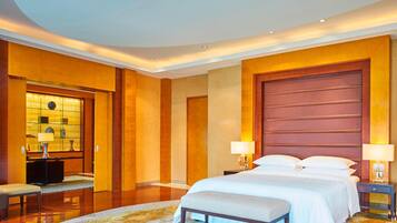 A hotel room with a large bed, bedside tables with lamps, a desk with a chair, and a large mirror.