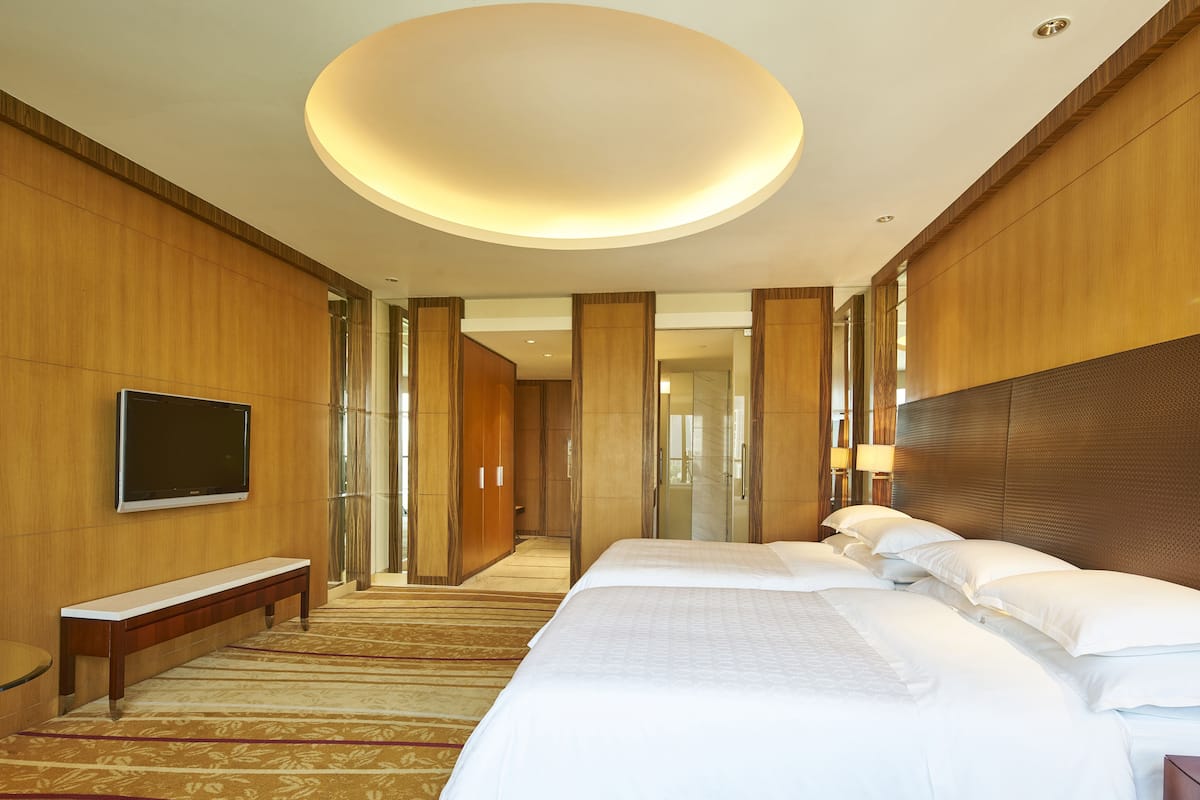 Habitación de hotel con una cama grande, televisión de pantalla plana, un banco y piso alfombrado.