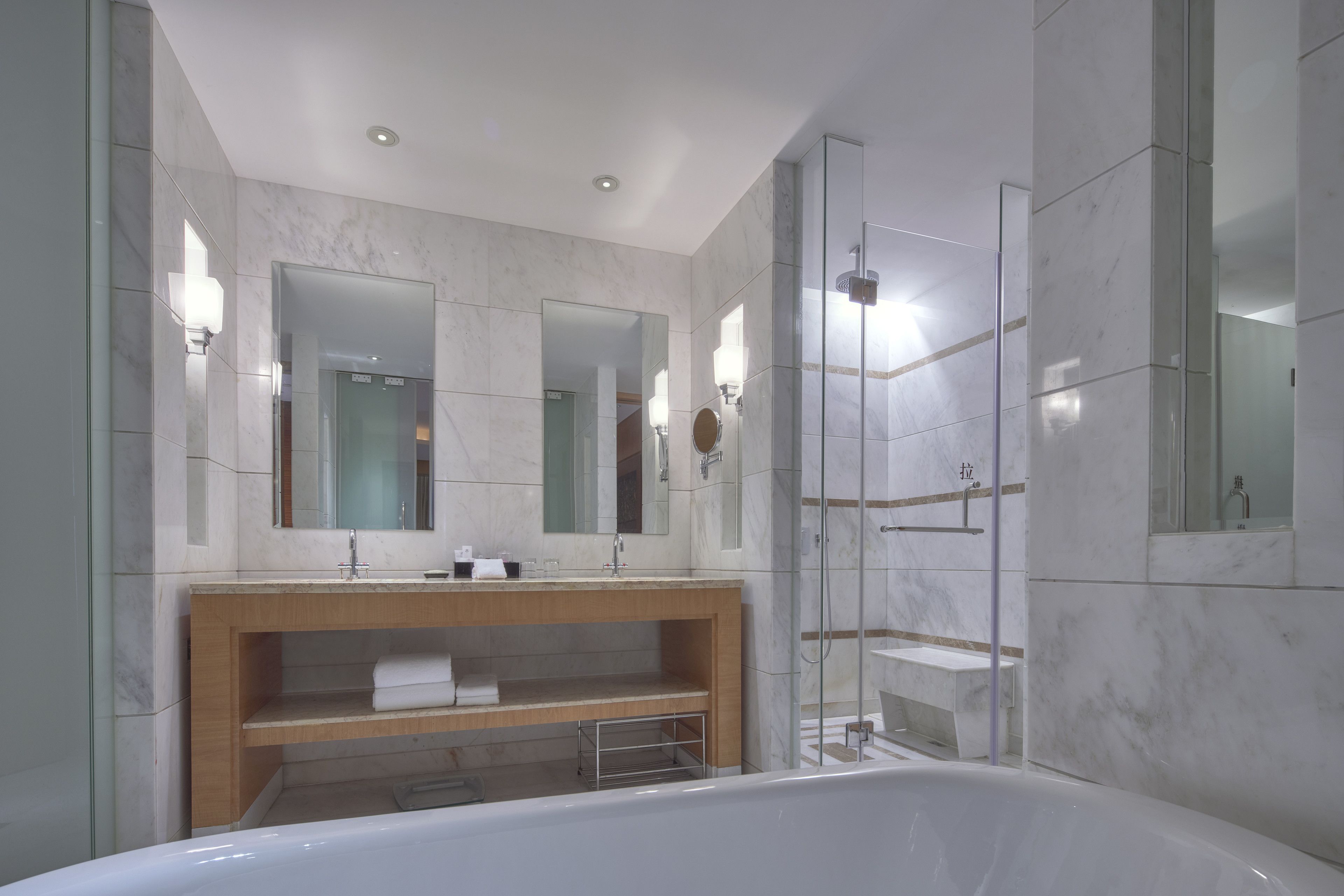 Une salle de bain moderne avec une grande baignoire, un meuble-lavabo en bois et une douche séparée par des parois de verre.