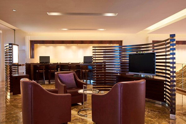 A modern lobby with leather seating, a reception desk, and a large TV screen. - Sheraton Zhoushan Hotel (Zhoushan)