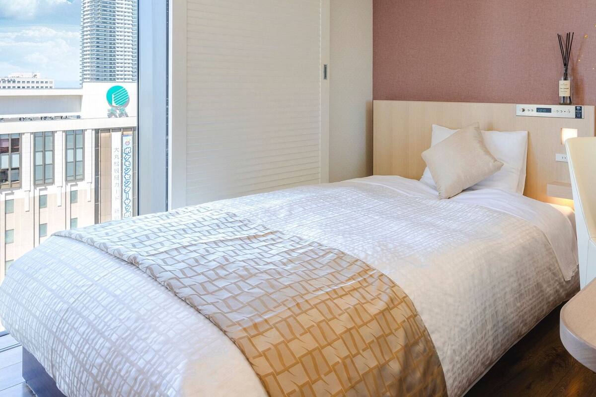 Una habitación de hotel con una cama, una silla y una mesa con una taza y un platillo.