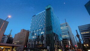 A modern high-rise building with a glass facade, surrounded by other buildings in an urban setting. - Hotel Gracery Sapporo (Sapporo)