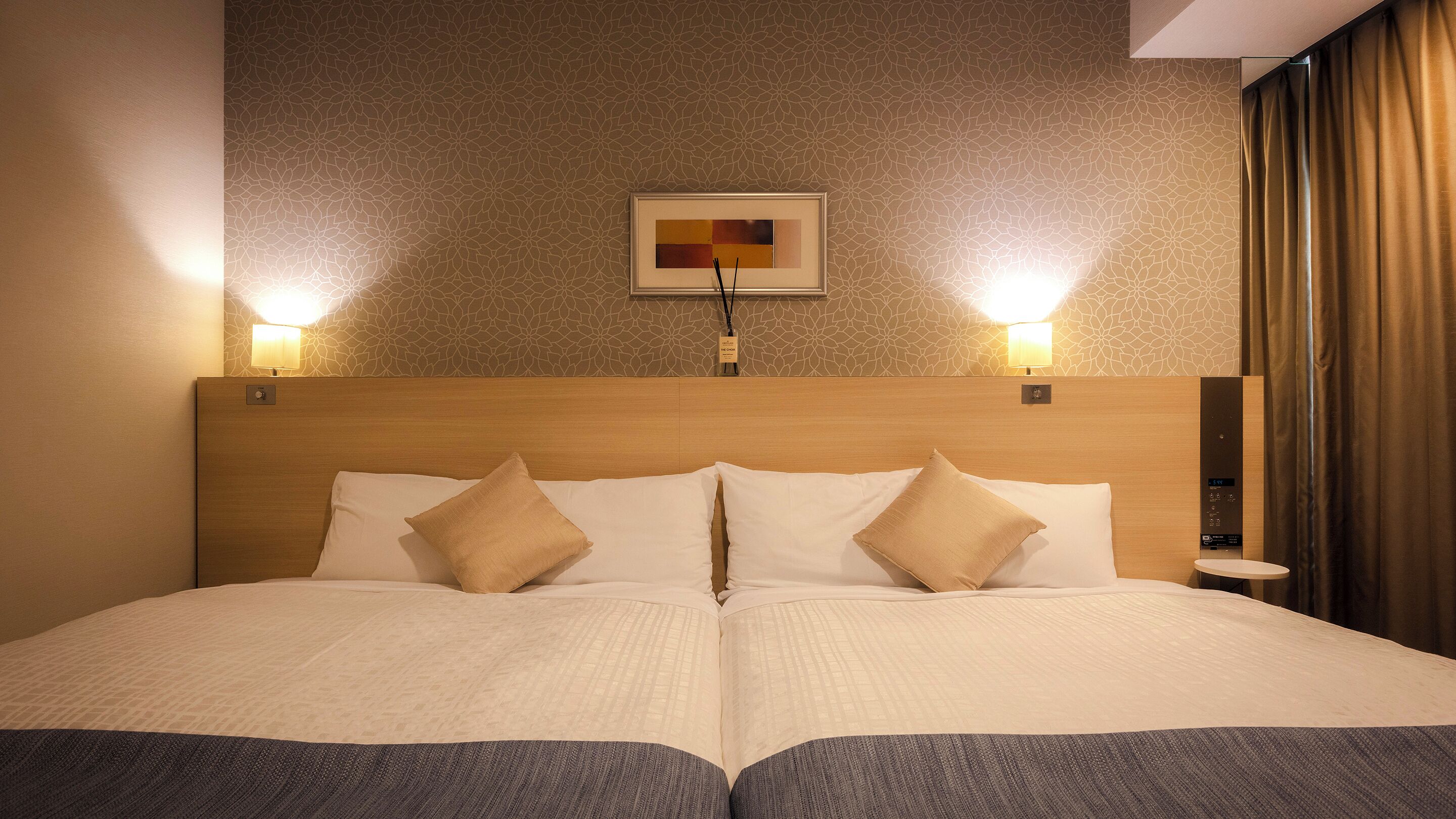 A double bed with a wooden headboard, two bedside lamps, and a framed artwork above the bed.